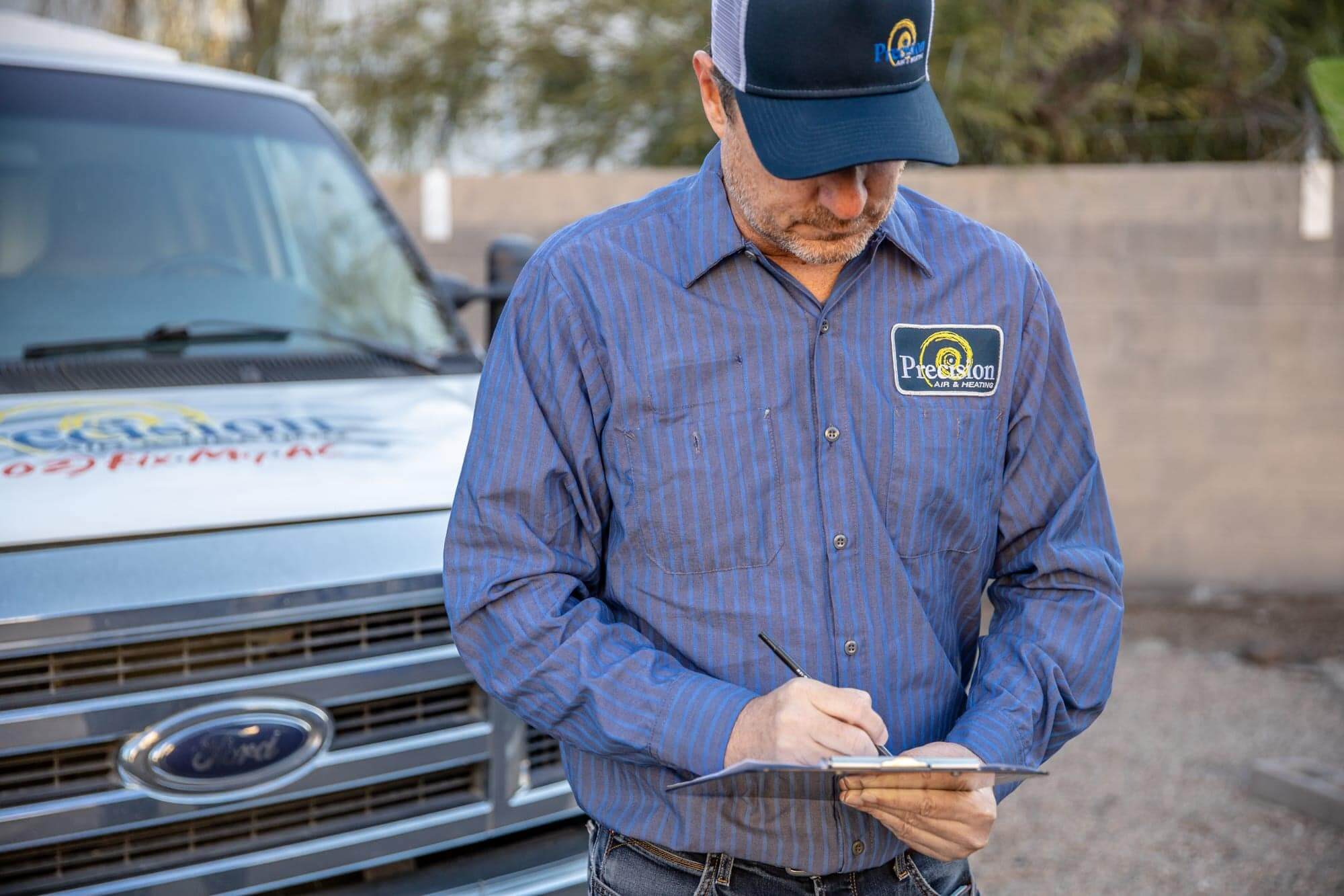 Precision AC Tech reviews work order in front of work truck