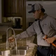 Plumbing technician inspecting kitchen sink and faucet