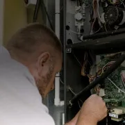 HVAC technician inspecting wiring inside furnace control panel